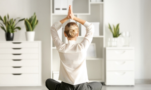 Young Businesswoman Meditating in Office, Back View