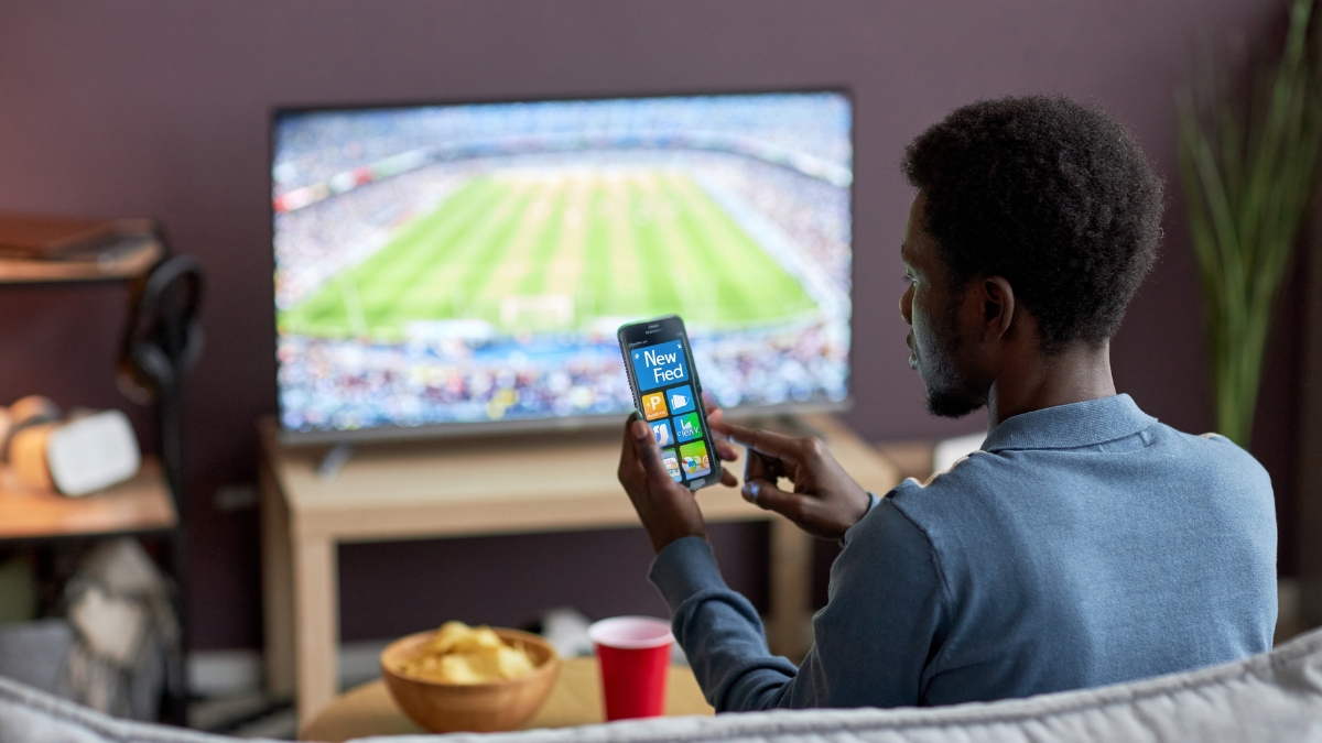 man watching tv with his phone